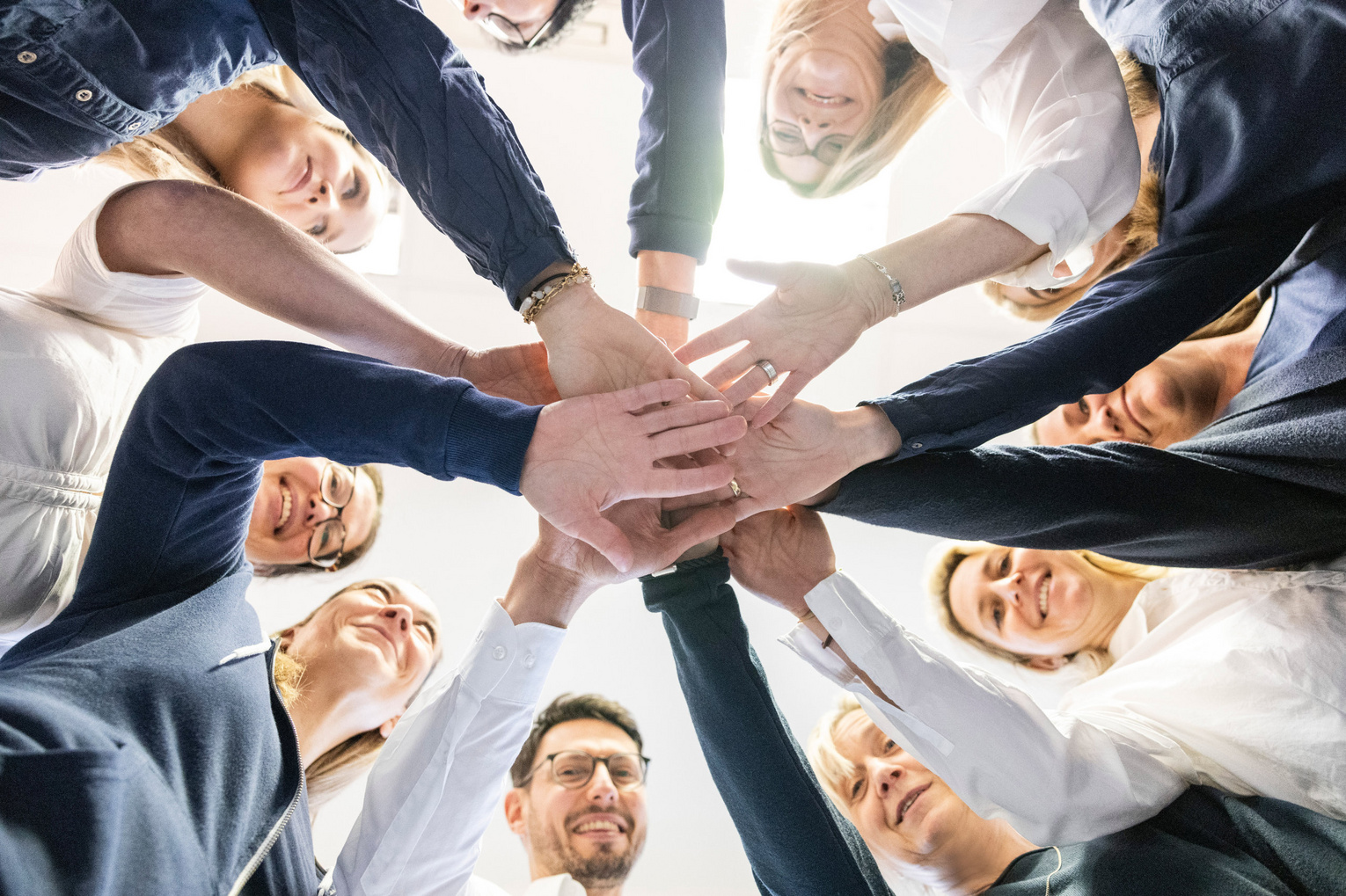 Teamfoto der Internistische Hausarztpraxis Dr. Andreas Kirsner Team der Hausarztprasix Dr. Kirsner hält Hände in der mitte zusammen.